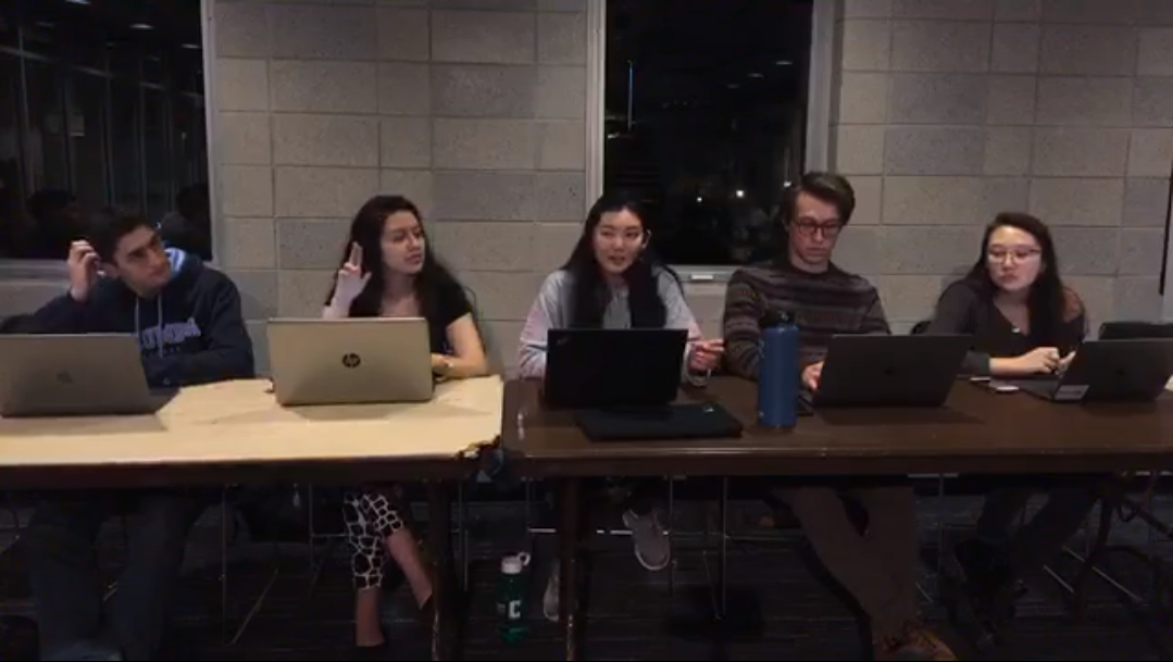 Five executive members of the engineering student council are sitting behind two long tables (one of tan color and the other of brown color) where they all have their laptops out and one of them is thinking while scratching his head and one of them is raising her hand as another is speaking. ESC meets every Monday from 9:30-10:30 pm in the Lerner Satow Room.