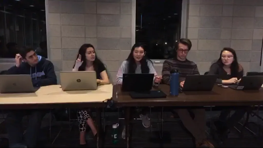 Five executive members of the engineering student council are sitting behind two long tables (one of tan color and the other of brown color) where they all have their laptops out and one of them is thinking while scratching his head and one of them is raising her hand as another is speaking. ESC meets every Monday from 9:30-10:30 pm in the Lerner Satow Room.